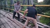Kapolsek Bonegunu, IPDA Zaifulah saat menutup lubang menganga di Jembatan Lahumoko. Foto: Adnan